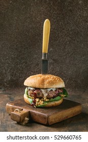 Hamburger With Beef Burger Cutlet, Fried Onion, Spinach, Ketchup Sauce And Blue Cheese In Traditional Buns, Served On Wood Chopping Board With Vintage Knife Over Dark Wooden Background.