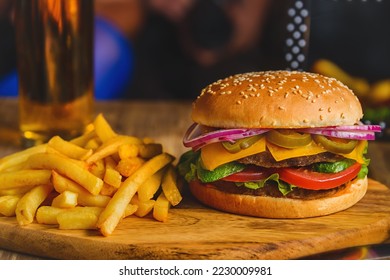 Hamburger with beef patty, cheese and onion near french fries and glass of apple juice on wooden brown table. American high-calorie fast food, quick snack - Powered by Shutterstock