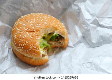 Hamburger With Bite Marks Placed On White Paper.