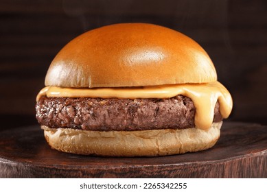 hamburguesa con crema de cheddar y un brioche fresco y sabroso sobre una mesa de humo y madera oscura.
