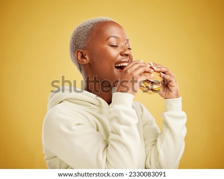 Hamburger, eating and happy woman or student on a studio, yellow background for restaurant promotion or deal. Hungry and excited african person or customer experience with fast food and burger bite