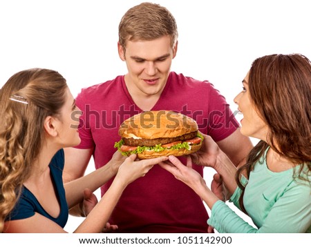 Hamburger fast food with ham in people hands. Fast food concept. Friends man and two women eating sandwich junk in party. Girls fool around and feed man. Feast on occasion of feast.