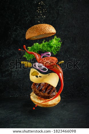 Hamburger with floating ingredients on dark background. Creative still life concept and advertisement