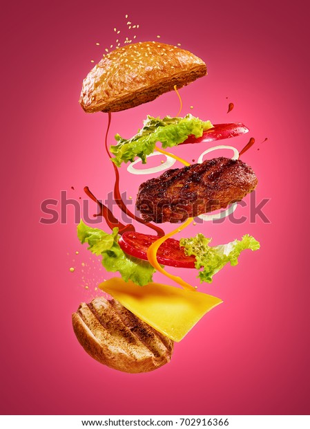 The
hamburger with flying ingredients on rose
background