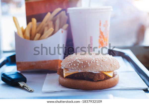 Hamburger, french fries, drink on tray\
standing from fastfood restaurant with key of\
car