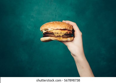 Hamburger in the hand, arm and hamburger, hamburger on a bright background