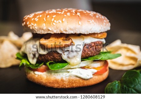 Hamburger vegetarian burger with falafel and vegetables salad tomato champignon and cheese tofu cheese all vegan food with nachos in blurred background