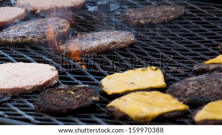 Hamburgers being flame broiled on the gas grill. Shallow depth of field.