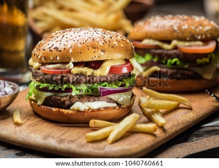 Hamburgers and French fries on the wooden tray.