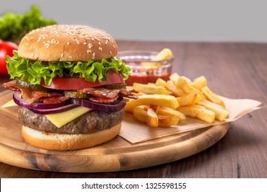 Hamburgers with fried bacon and sliced pickles  on a cutting board with french fries and tomato sauce - Powered by Shutterstock