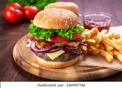 Hamburgers with fried bacon and sliced pickles  on a cutting board with french fries and ketchup - Powered by Shutterstock