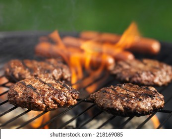 Hamburgers And Hotdogs Cooking On Grill Outdoors