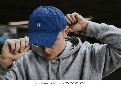 Hamdsome young man wearing blue baseball cap. Young man in street fashion wearing hoodie and blue cap. Portrait photo of man in stylish blue baseball cap and trendy hoodie.