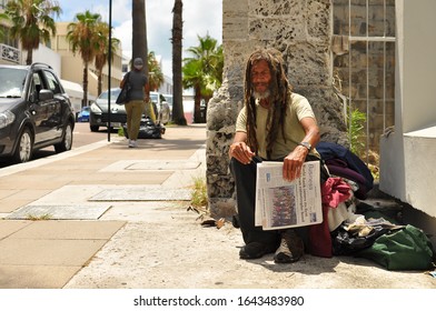 Hamilton, Bermuda - July 10, 2014:An old homeless black man with dreadlocks sitting on the street with a newspaper in his hand.