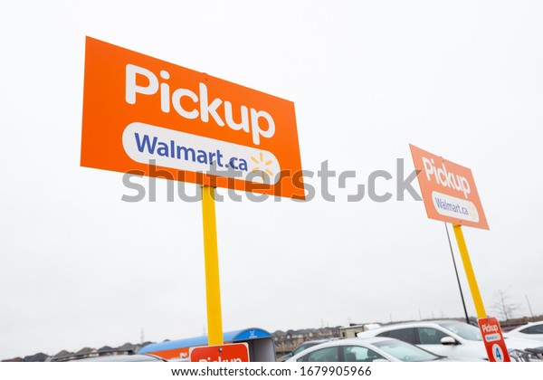 Hamilton, Ontario /\
Canada - March 2020: Grocery pickup signs in the parking lot of a\
Walmart Canada\
supercentre.