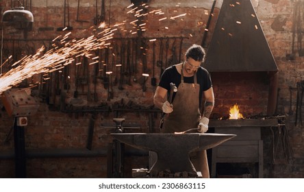 Hammer, anvil and fire with a man working in a factory for metal work manufacturing or production. Industry, welding and trade with a male blacksmith at work in a forge, plant or industrial workshop - Powered by Shutterstock