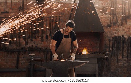 Hammer, anvil and fire with a man working in a plant for metal work manufacturing or production. Industry, welding and trade with a male blacksmith at work in a factory, forge or industrial workshop - Powered by Shutterstock