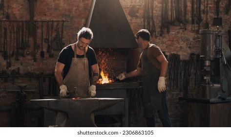 Hammer, anvil and fire with men working in a foundry for metal work manufacturing or production. Industry, welding and trade with blacksmith craftsmen in a steel workshop, plant or industrial forge - Powered by Shutterstock