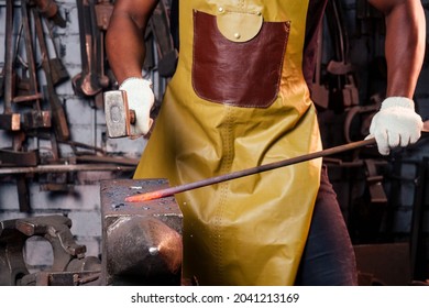 Hammer Industry Small Business Concept.african American Man Dressed In Historical Clothing Is Hammering On The Anvil. A Blacksmith Forges A Metal Product