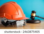 Hammer judge gavel with construction hat helmet, worker safety glasses on wooden table. Labour law concept. Wages, overtime pay, welfare, occupational safety, health, environment, severance pay.