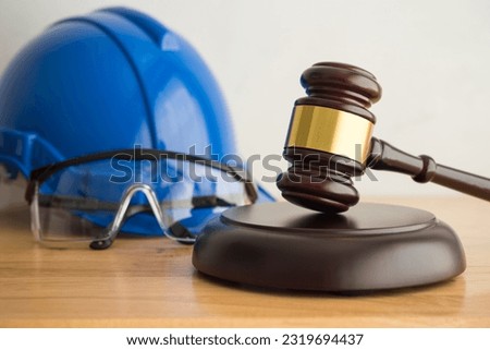 Hammer judge gavel with construction hat helmet, worker safety glasses on wooden background. Labour law concept. Wages, overtime pay, welfare, occupational safety, health, environment, severance pay.