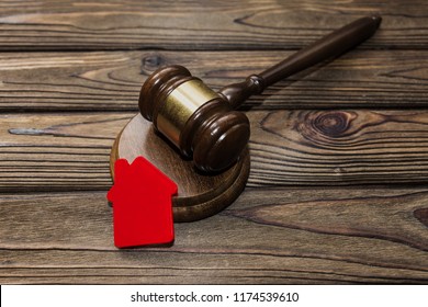 Hammer Of The Judge, The House Against The Background Of A Wooden Table. Finance. Sale Of Real Estate Property Seizure.