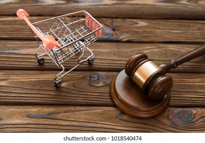 hammer of the judge, a trolley from a supermarket on a wooden background. consumer rights Protection.