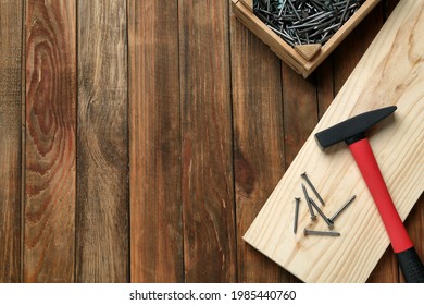 Hammer, metal nails, plank and crate on wooden table, flat lay. Space for text - Shutterstock ID 1985440760