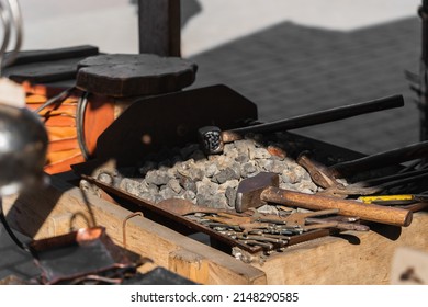 Hammers and blacksmith tools lie on black coal with metal blanks for forging in the sunlight, old professions and manual labor in the modern world - Powered by Shutterstock