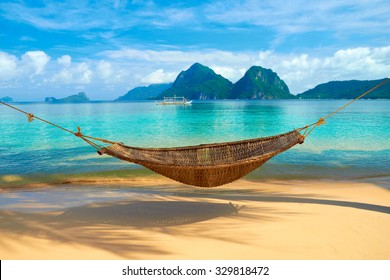 A hammock at the beach with the view of Bacuit Archipelago islands (El Nido, Philippines)