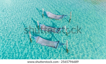 Hammocks gently sway above the stunning turquoise waters of Koh Kood, Thailand, inviting visitors to unwind in nature's paradise. The sunlit waves create a serene atmosphere for relaxation.