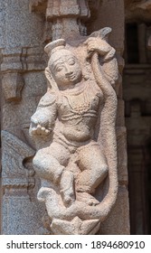 Hampi, Karnataka, India - November 5, 2013: Vijaya Vitthala Temple. Closeup of Beige stone statue of gracious smiling woman with snake. 