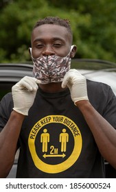 Hampshire, England, UK. 2020, Man Adjusting His Face Mask And Wearing Please Keep Your Distance  Shirt During The Covid Outbreak.