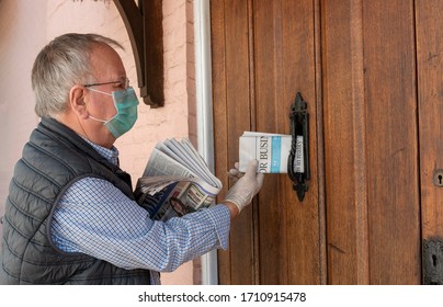 Hampshire, UK.2020. Newspaper Delivery Man Wearing Protective Mask And Surgical Gloves While Delivering Newspapers To A Country Home.