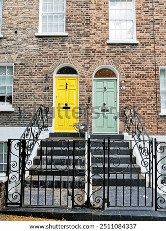 Hampstead: view of bright yellow front door and light green front door. Staircase and railings. British building of bricks and windows.