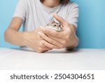 Hamster in the hands of the owner, dzungarian rodent eating, cute mammal in care.