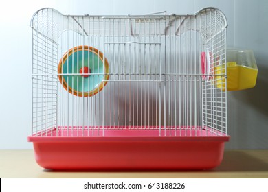 Hamster Wheel In Old And Empty Hamster White And Pink Cage On Wood Desk