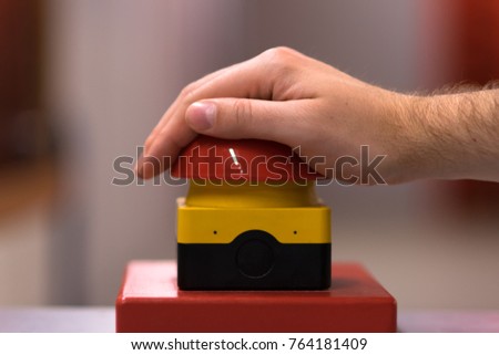 Hand above a red emergency button