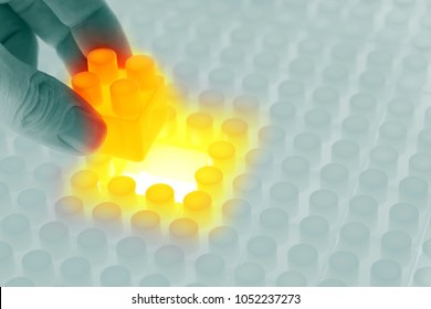 hand adding the final piece to toy block surface, abstract concept