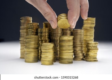 Hand adding money to stacks of assorted Euro coins Stock Photo