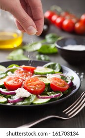 Hand Adding Salt To Vegetable Salad 