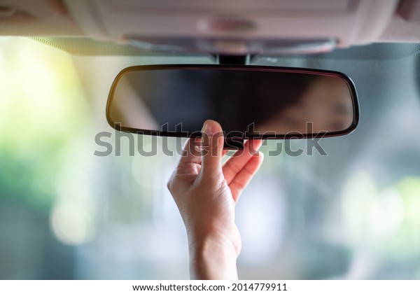 Hand adjusting rear view\
mirror.\
