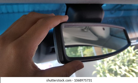  hand adjusting a rearview mirror