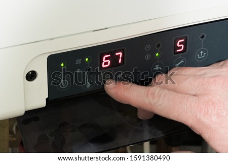 Hand adjusting the temperature on a combination boiler