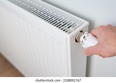 Hand adjusting temperature on heating radiator thermostat, Turning heat radiator knob to control heat in home - Shutterstock ID 2108001767