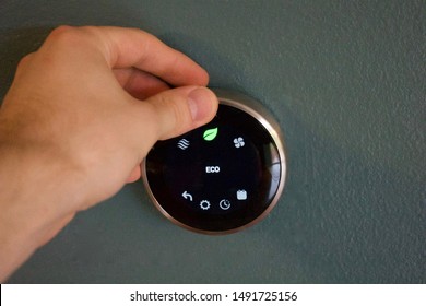 Hand Adjusting Temperature To Save Money Using Smart Thermostat