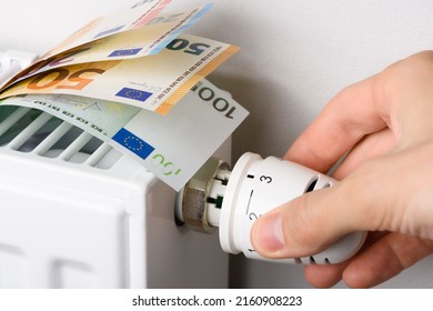 Hand Adjusting The Valve Knob Of Heating Radiator Temperature Thermostat With Of Euro Money Banknotes In It. Expensive Heating Costs And Rising Energy Bill Prices For Winter Cold Season
