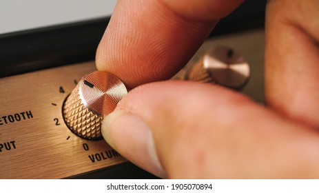 Hand adjusting volume control.Use hand to adjust the volume at the volume control button of the amplifier. - Shutterstock ID 1905070894
