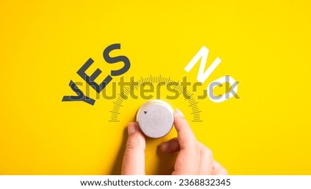 Hand adjusting the volume selector for choosing YES or NO on isolated yellow background. Questionnaire question and answer concept.