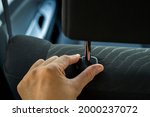 Hand adjusts headrest in car interior. adjusting the seat position in the car